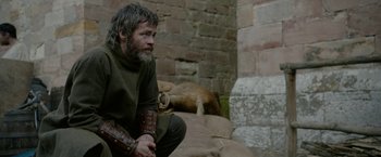 Movie still from “Outlaw King” (2018), directed by David Mackenzie – A man sitting on the ground in a room; Medium shot, Over the shoulder angle