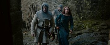 Movie still from “Outlaw King” (2018), directed by David Mackenzie – A group of people walking down a stone path; Medium shot, Low angle