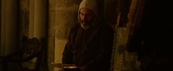 Movie still from “Outlaw King” (2018), directed by David Mackenzie – A man with a beard wearing a white hat and holding a tablet; Medium shot, Low angle