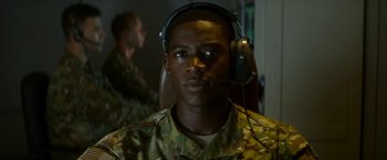 Movie still from “Outside the Wire” (2021), directed by Mikael Håfström – A man in a military uniform wearing a headset; Close Up shot, Over the shoulder angle
