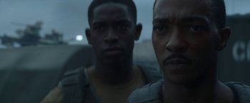 Movie still from “Outside the Wire” (2021), directed by Mikael Håfström – Two men are standing next to each other in the dark; Close Up shot, Over the shoulder angle