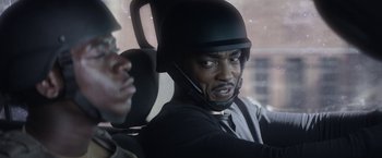 Movie still from “Outside the Wire” (2021), directed by Mikael Håfström – A man wearing a helmet while sitting in a car; Close Up shot, Over the shoulder angle