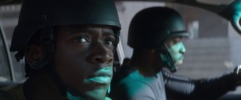 Movie still from “Outside the Wire” (2021), directed by Mikael Håfström – A man with a helmet on is looking at the camera; Close Up shot, Over the shoulder angle