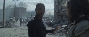 Movie still from “Outside the Wire” (2021), directed by Mikael Håfström – A man standing in front of a pile of rubble; Medium shot, Over the shoulder angle