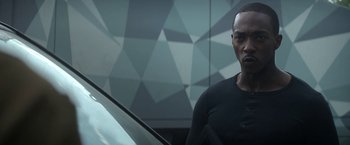 Movie still from “Outside the Wire” (2021), directed by Mikael Håfström – A man standing in front of a car in front of a building; Close Up shot, Over the shoulder angle