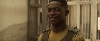 Movie still from “Outside the Wire” (2021), directed by Mikael Håfström – A person smiling for the camera; Close Up shot, Over the shoulder angle