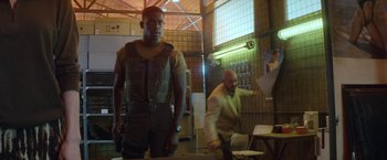 Movie still from “Outside the Wire” (2021), directed by Mikael Håfström – A man standing next to another man in a room; Medium shot, Low angle