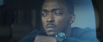 Movie still from “Outside the Wire” (2021), directed by Mikael Håfström – A person holding a watch in a car; Close Up shot, Low angle