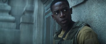 Movie still from “Outside the Wire” (2021), directed by Mikael Håfström – A young man is looking into the camera; Close Up shot, Over the shoulder angle