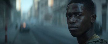 Movie still from “Outside the Wire” (2021), directed by Mikael Håfström – A man's face in a city street; Close Up shot, Low angle