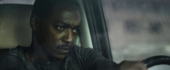 Movie still from “Outside the Wire” (2021), directed by Mikael Håfström – A man sitting in a car looking at the camera; Close Up shot, Low angle