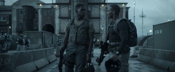 Movie still from “Outside the Wire” (2021), directed by Mikael Håfström – A couple of men standing next to each other holding guns; Medium shot, Over the shoulder angle