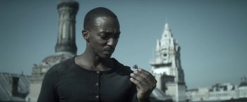 Movie still from “Outside the Wire” (2021), directed by Mikael Håfström – A man looking at a ring in his hand; Close Up shot, Low angle