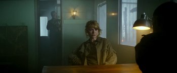 Movie still from “Outside the Wire” (2021), directed by Mikael Håfström – A woman sitting at a table in front of a window; Medium shot, Over the shoulder angle