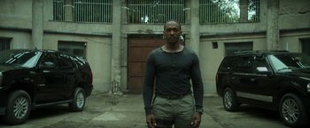 Movie still from “Outside the Wire” (2021), directed by Mikael Håfström – A man standing in front of a garage door; Medium shot, Low angle