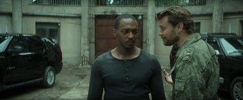 Movie still from “Outside the Wire” (2021), directed by Mikael Håfström – Two men talking to each other in an alley way; Medium shot, Over the shoulder angle