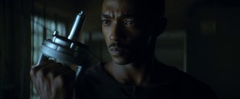 Movie still from “Outside the Wire” (2021), directed by Mikael Håfström – A person holding a gun in a dark room; Close Up shot, Low angle