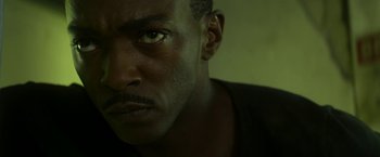 Movie still from “Outside the Wire” (2021), directed by Mikael Håfström – A man's face in a dark room; Close Up shot, Low angle