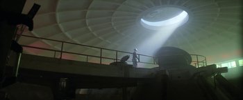 Movie still from “Outside the Wire” (2021), directed by Mikael Håfström – A man standing on a platform in a building; Extreme Wide shot, Low angle
