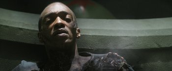 Movie still from “Outside the Wire” (2021), directed by Mikael Håfström – A person with a tattoo on his face; Close Up shot, Overhead angle