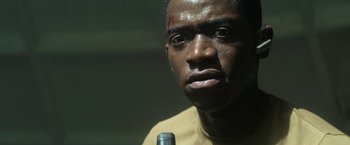 Movie still from “Outside the Wire” (2021), directed by Mikael Håfström – A person holding a microphone; Close Up shot, Low angle