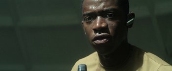 Movie still from “Outside the Wire” (2021), directed by Mikael Håfström – A person with a microphone; Close Up shot, Low angle