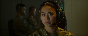 Movie still from “Outside the Wire” (2021), directed by Mikael Håfström – A woman in a military uniform wearing a headset; Close Up shot, Over the shoulder angle