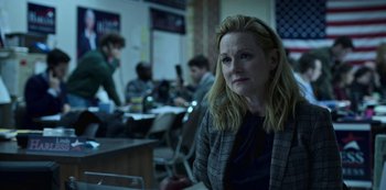 Movie still from “Ozark” (2017), created by Bill Dubuque – A woman sitting in front of a group of people in a room; Medium shot, Over the shoulder angle