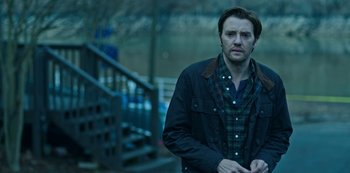 Movie still from “Ozark” (2017), created by Bill Dubuque – A man standing in front of a railing and stairs; Medium shot, Over the shoulder angle