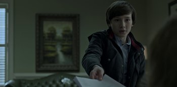 Movie still from “Ozark” (2017), created by Bill Dubuque – A young man holding a piece of paper in his hand; Medium shot, Over the shoulder angle