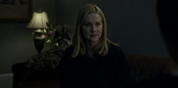 Movie still from “Ozark” (2017), created by Bill Dubuque – A woman sitting on a couch in a dark room; Medium shot, Over the shoulder angle