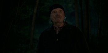 Movie still from “Ozark” (2017), created by Bill Dubuque – An old man wearing a black hat standing in the dark; Medium shot, Low angle