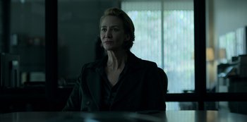 Movie still from “Ozark” (2017), created by Bill Dubuque – A woman sitting at a table in front of a computer screen; Medium shot, Low angle