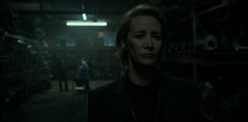 Movie still from “Ozark” (2017), created by Bill Dubuque – A woman in a black jacket is standing in a dark room; Close Up shot, Over the shoulder angle