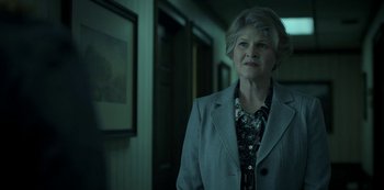Movie still from “Ozark” (2017), created by Bill Dubuque – An older woman standing in front of a painting; Medium shot, Over the shoulder angle