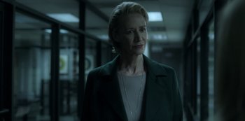 A woman with short blonde hair standing in a dark room