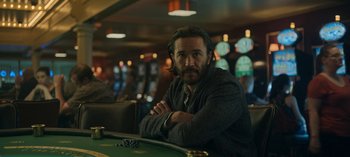 Movie still from “Ozark” (2017), created by Bill Dubuque – A man sitting at a table in front of cards; Medium shot, Over the shoulder angle