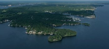 Movie still from “Ozark” (2017), created by Bill Dubuque – An aerial view of a small island in the middle of a body of water; Extreme Wide shot, High angle