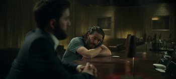 Movie still from “Ozark” (2017), created by Bill Dubuque – A man sitting at a table with another man in the background; Medium shot, Over the shoulder angle