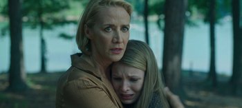 A woman and a girl are hugging in a forest