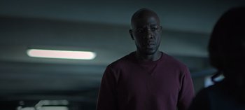 Movie still from “Ozark” (2017), created by Bill Dubuque – A man standing in a dark room wearing a red shirt; Close Up shot, Low angle