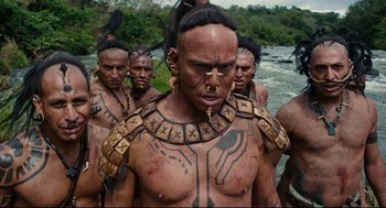 Movie still from “Apocalypto” (2006), directed by Mel Gibson – A group of men standing next to each other in front of a body of water; Medium shot, Low angle