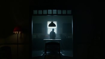 Movie still from “Mr. Robot” (2015), created by Sam Esmail – A man sitting at a table in a dark room; Wide shot, Low angle