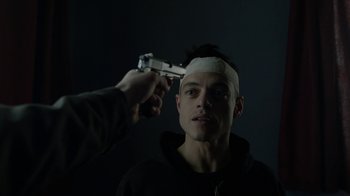 Movie still from “Mr. Robot” (2015), created by Sam Esmail – A man with bandages on his head is holding a gun pointed at him; Close Up shot, Low angle
