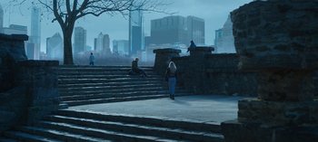 People are sitting and standing on some steps in a park