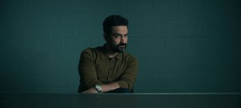 Movie still from “Ozark” (2017), created by Bill Dubuque – A man sitting at a table with his arms crossed; Medium shot, Low angle
