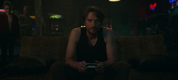 Movie still from “Ozark” (2017), created by Bill Dubuque – A man sitting on top of a couch holding a nintendo wii game controller; Medium shot, Low angle