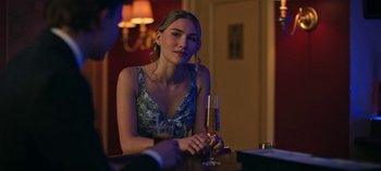 Movie still from “Ozark” (2017), created by Bill Dubuque – A beautiful young lady sitting at a table with a glass of champagne; Medium shot, Over the shoulder angle