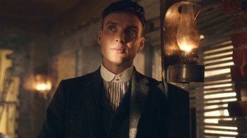 Movie still from “Peaky Blinders” (2013), created by Steven Knight – A man wearing a suit and tie standing next to a street light; Close Up shot, Low angle