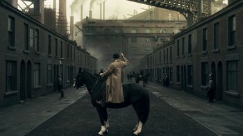 Movie still from “Peaky Blinders” (2013), created by Steven Knight – A man riding on the back of a black horse; Extreme Wide shot, High angle